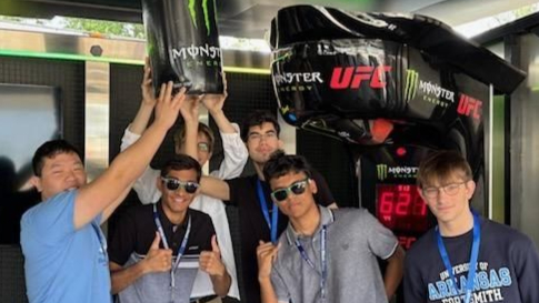 Group photo of Walmart Global Tech interns at a Walmart expo, some holding up an inflatable Monster drink